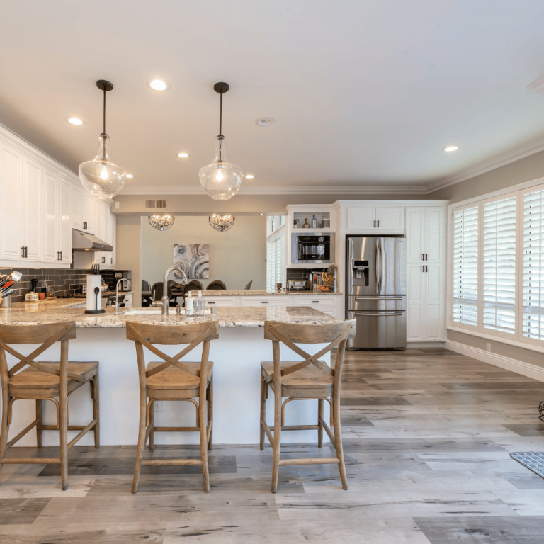 A kitchen with granite countertops, hardwood floors, and an island with bar stools.