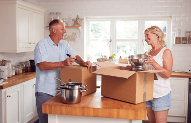 A couple unpacking boxes in their new home, smiling and sorting through their belongings, with items scattered around and a sense of excitement in the air.