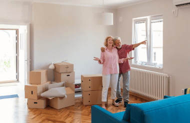 A couple sorting through their belongings as they downsize, discussing which items to keep and which to donate, surrounded by boxes and organized clutter in a cozy room.